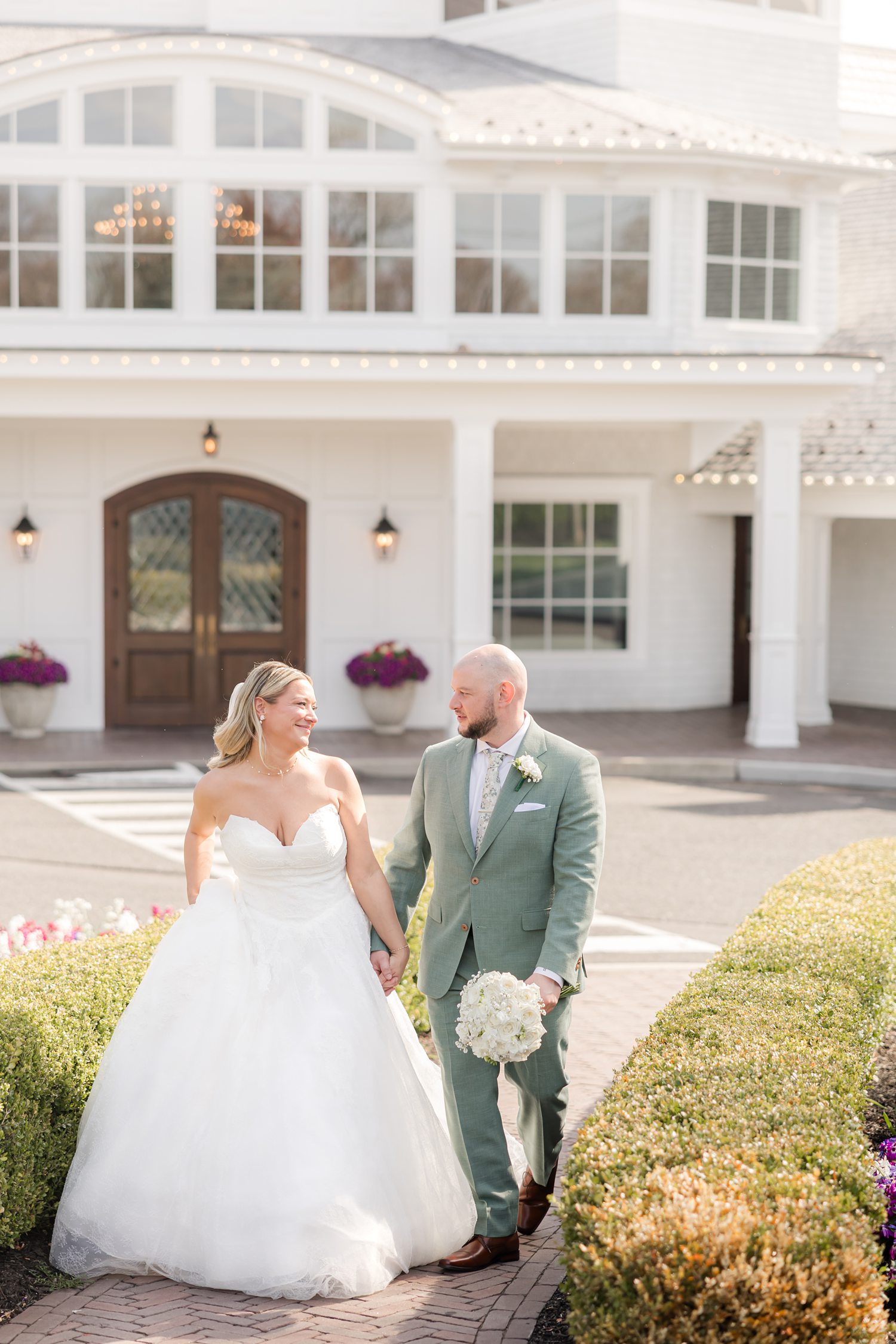 Newlywed couple posing outside elegant manor wedding venue entrance