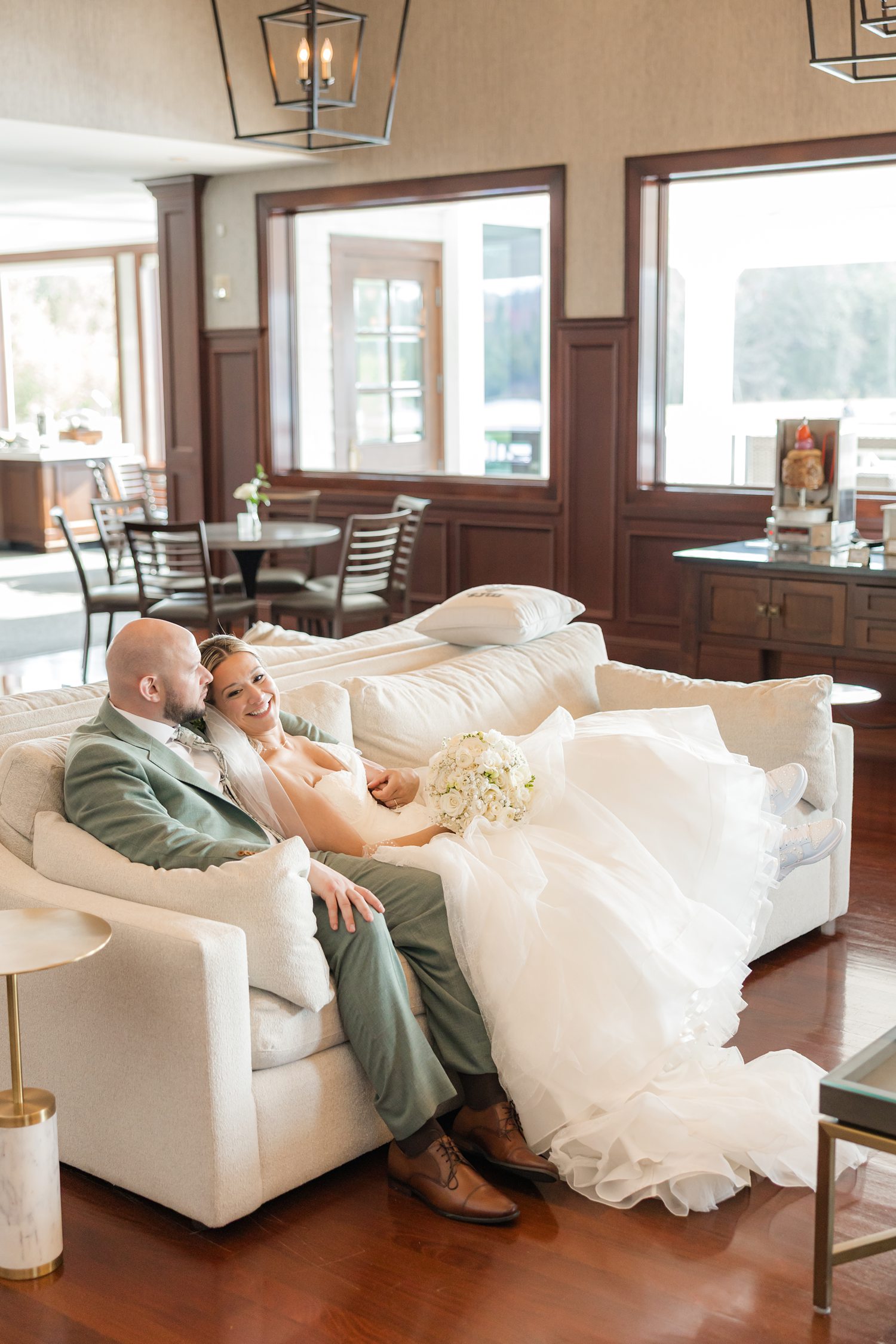 Bride and groom cuddling on couch in luxury wedding venue lounge area
