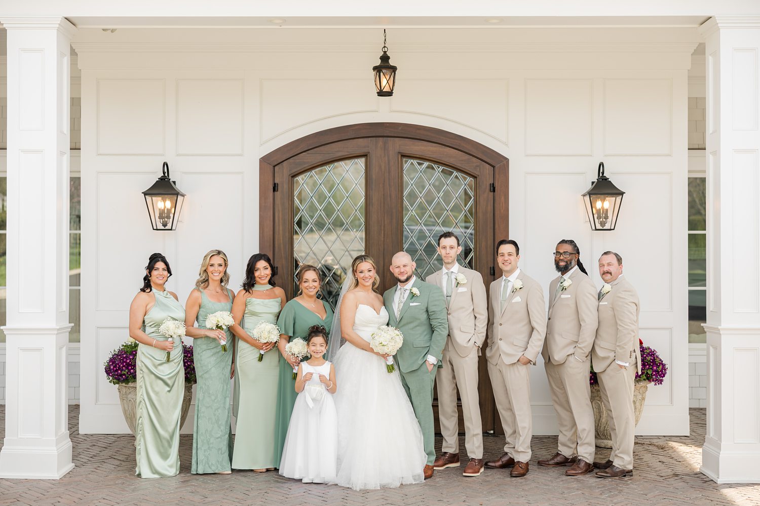 Bridal party and groomsmen posing in front of elegant wedding venue entrance