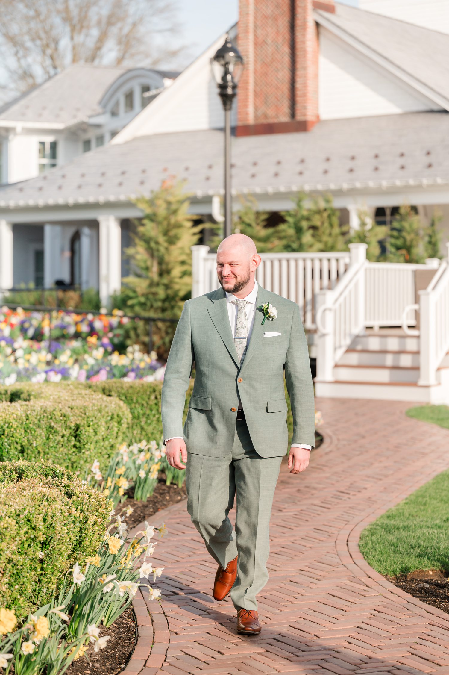 Groom walking confidently outside luxury lakeside wedding venue before ceremony
