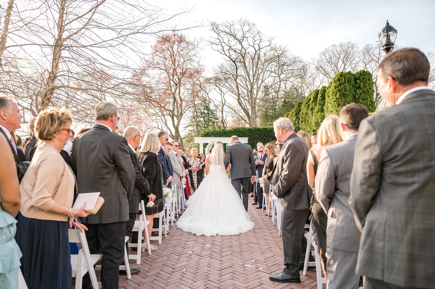 Guests watching bride arrive during elegant outdoor wedding ceremony