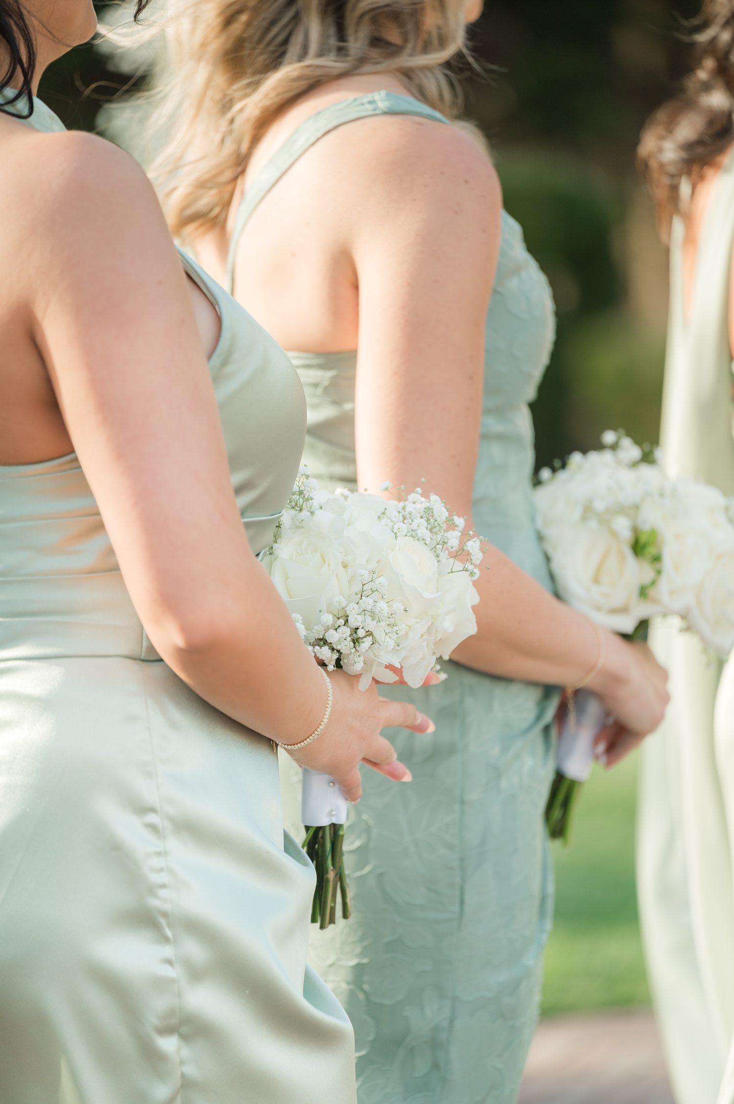 Bridesmaid holding white bouquet in sage green dress during ceremony