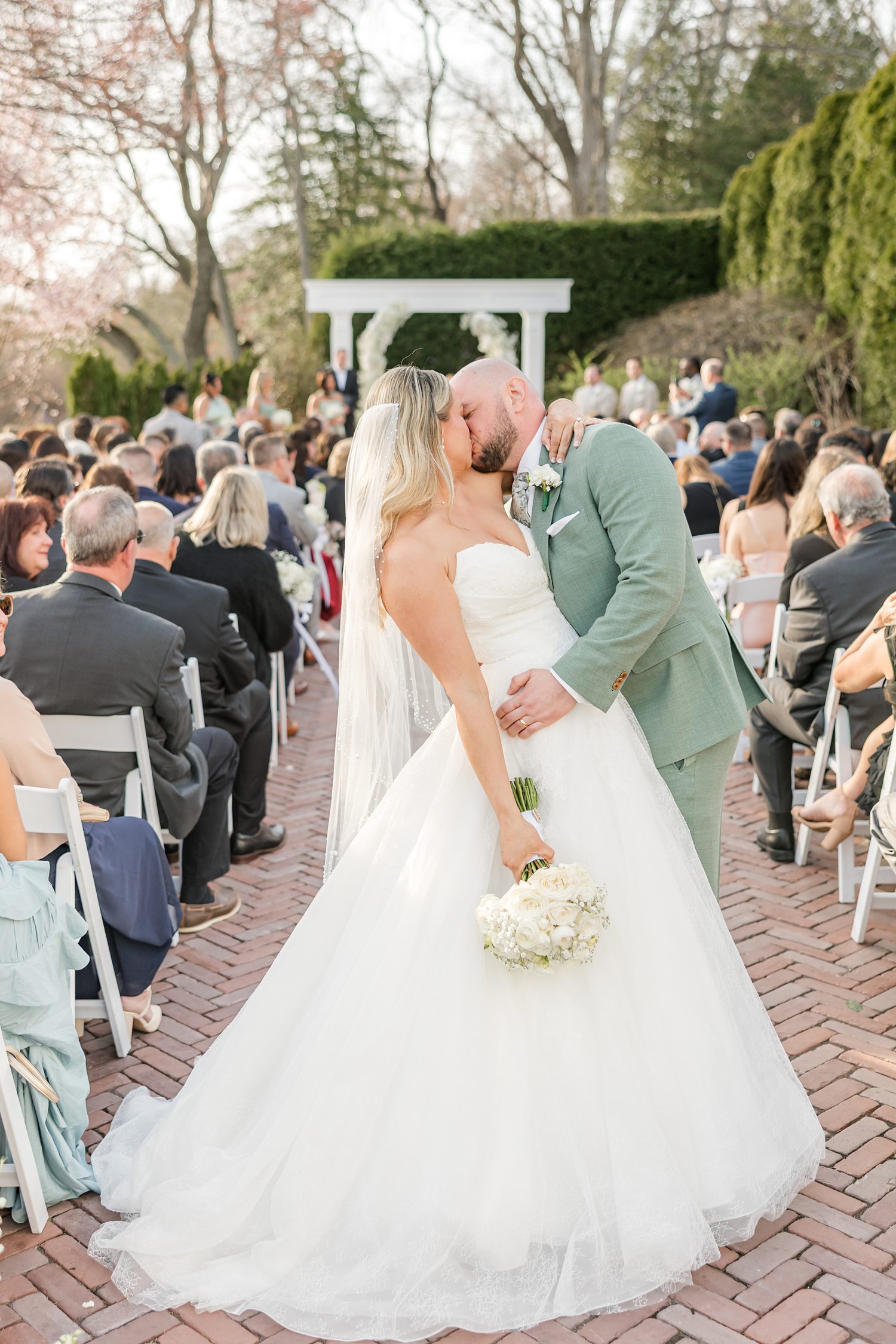 Newlywed couple kissing after outdoor wedding ceremony celebration