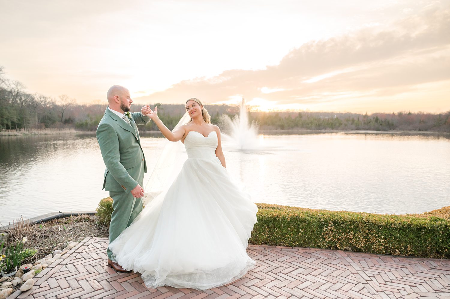Bride and groom dancing beside lakeside view during sunset wedding session