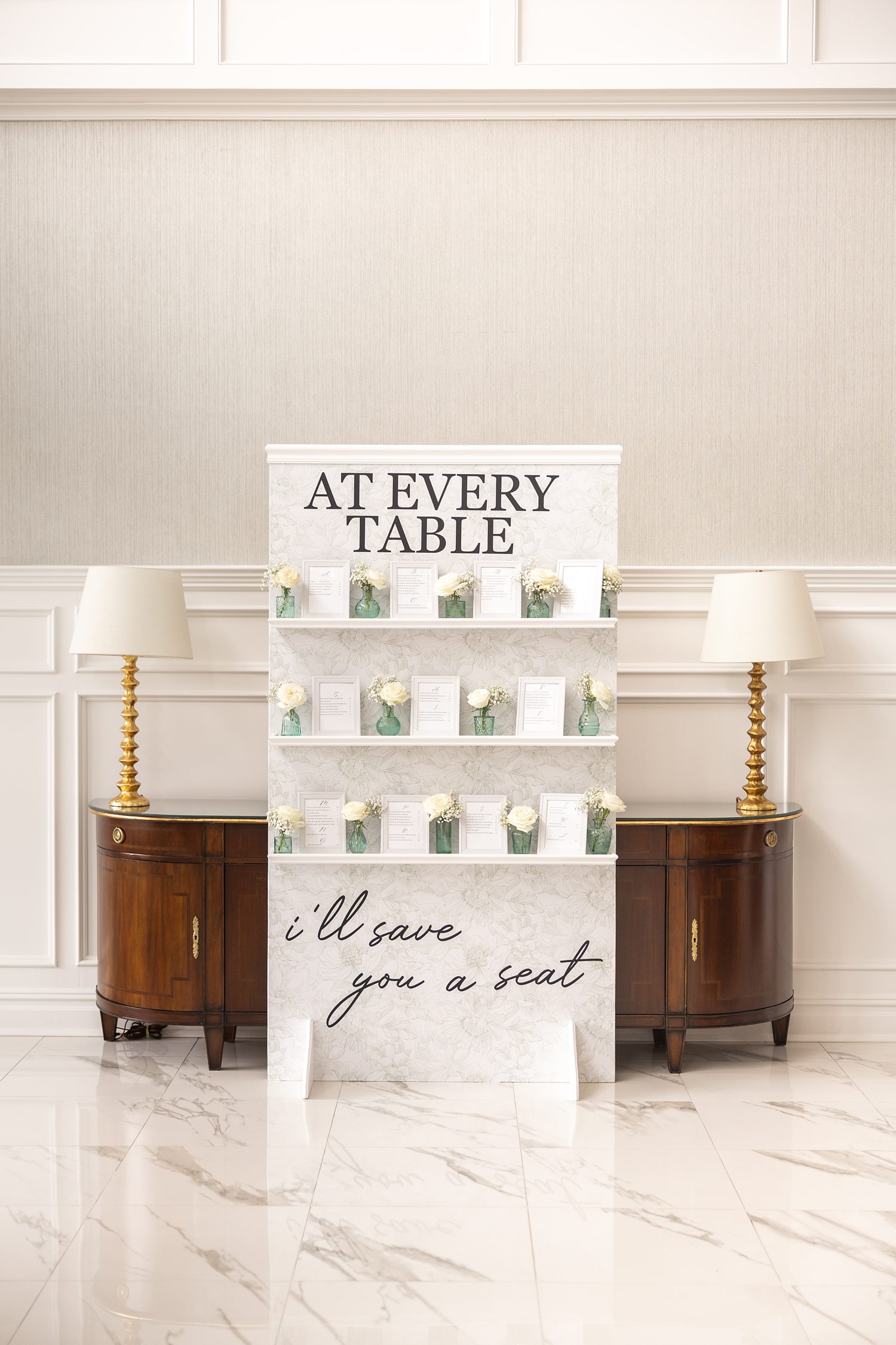 Elegant wedding seating chart display with white floral decor indoors