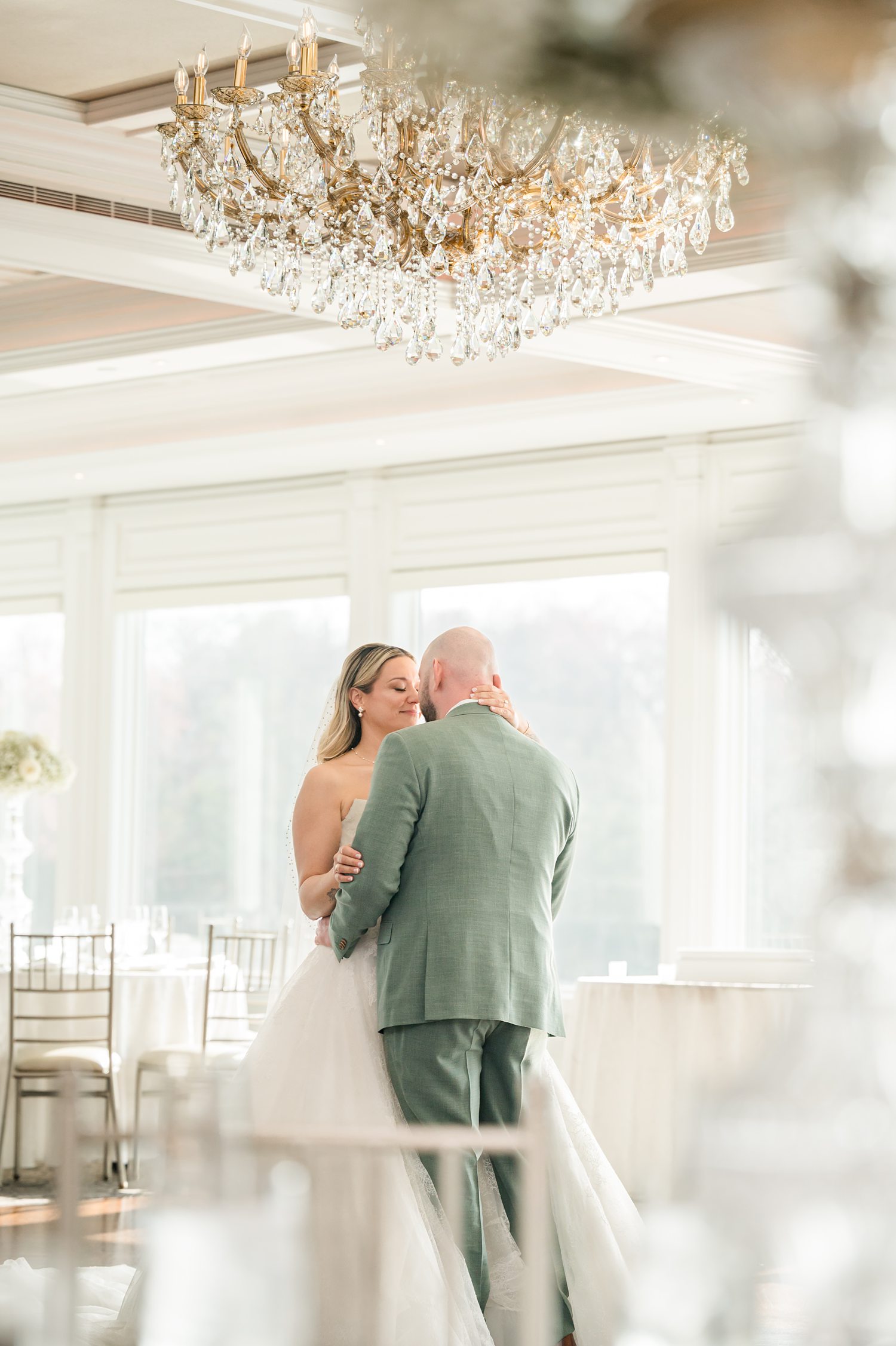 Bride and groom embracing inside elegant ballroom with crystal chandeliers