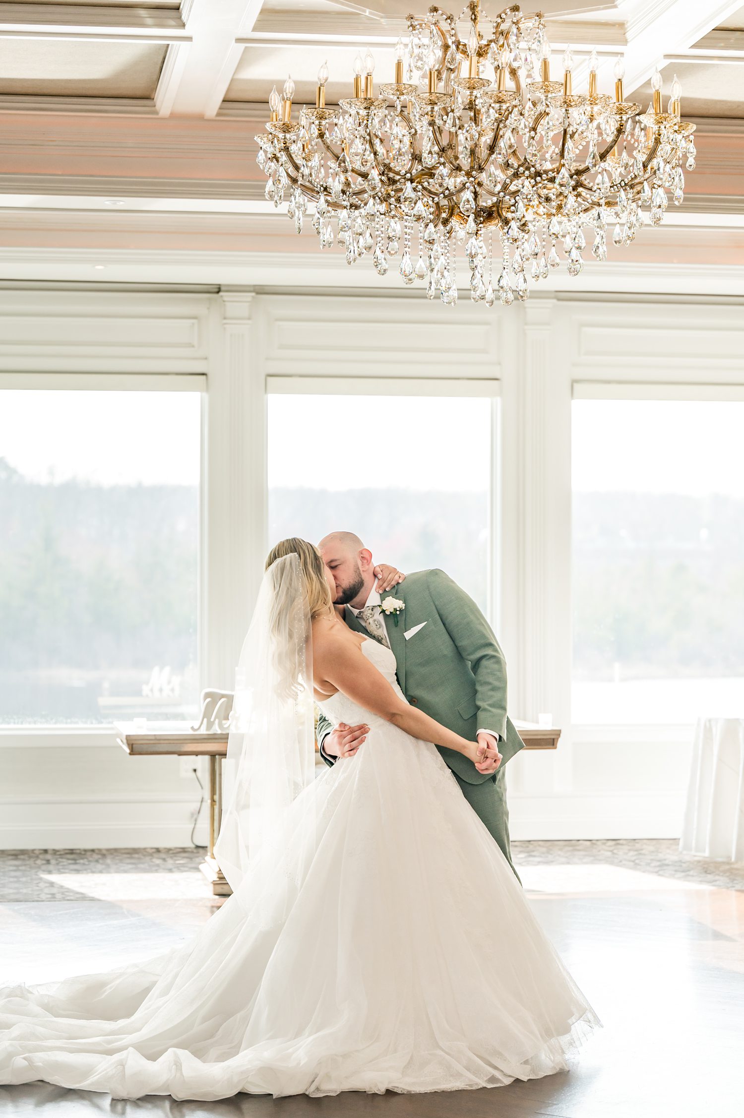 Bride and groom sharing intimate dance beneath chandelier-lit ballroom ceiling