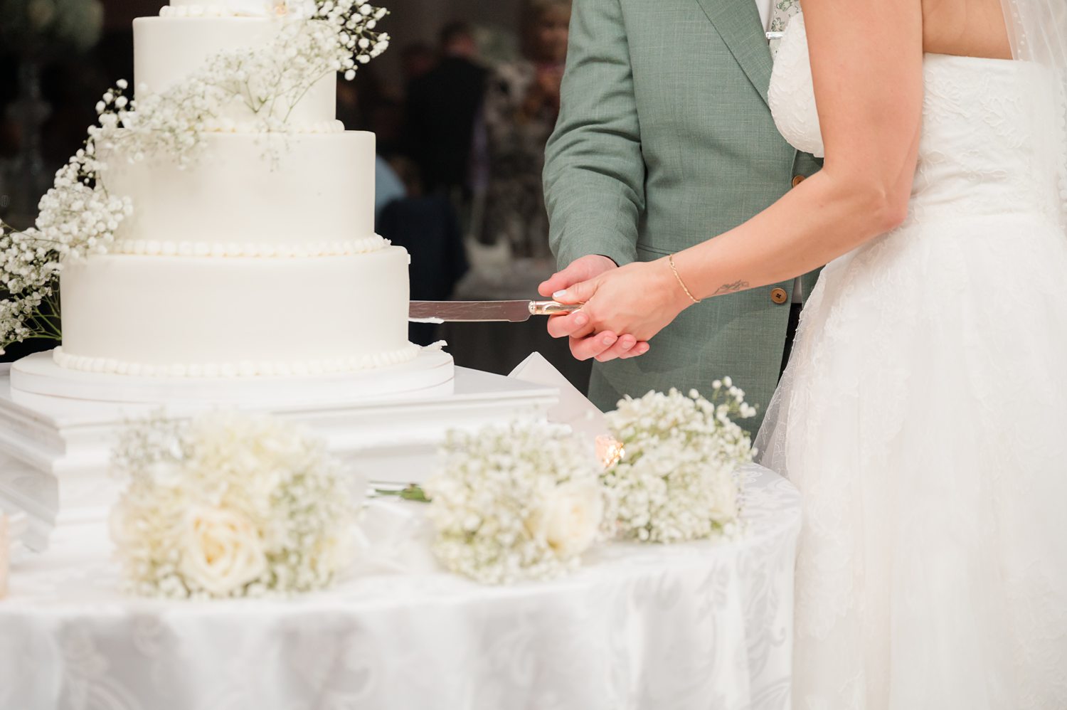Bride cutting luxury wedding cake with white floral decorations
