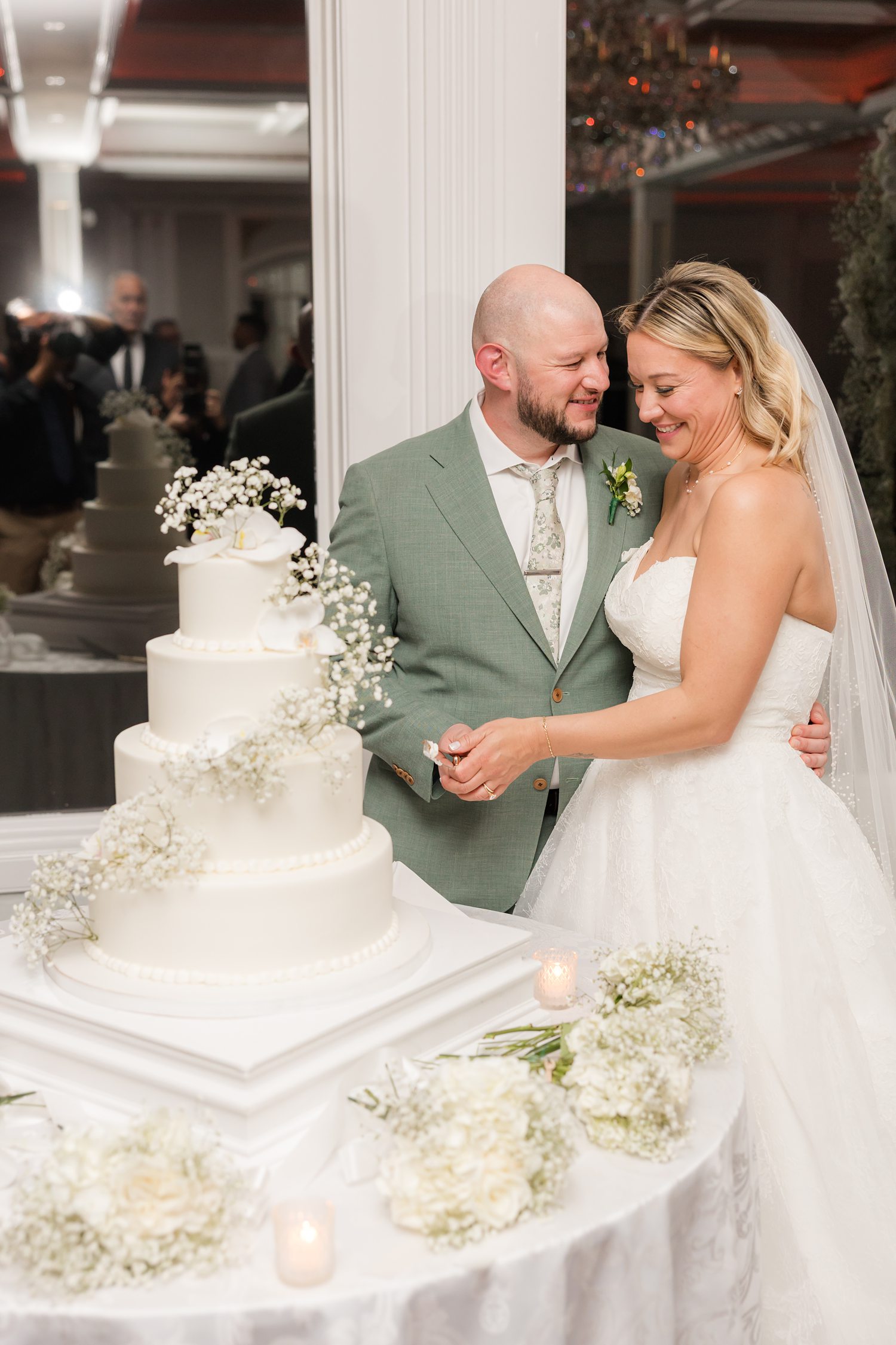 Newlywed couple smiling beside multi-tier wedding cake during reception