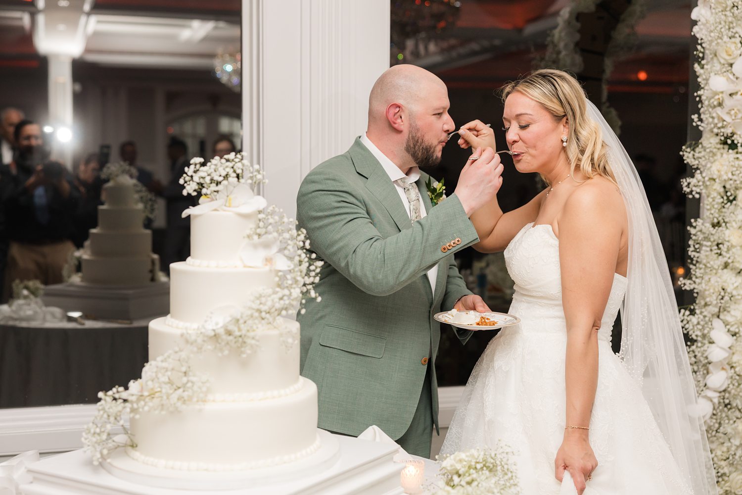 Groom feeding bride wedding cake during romantic reception celebration