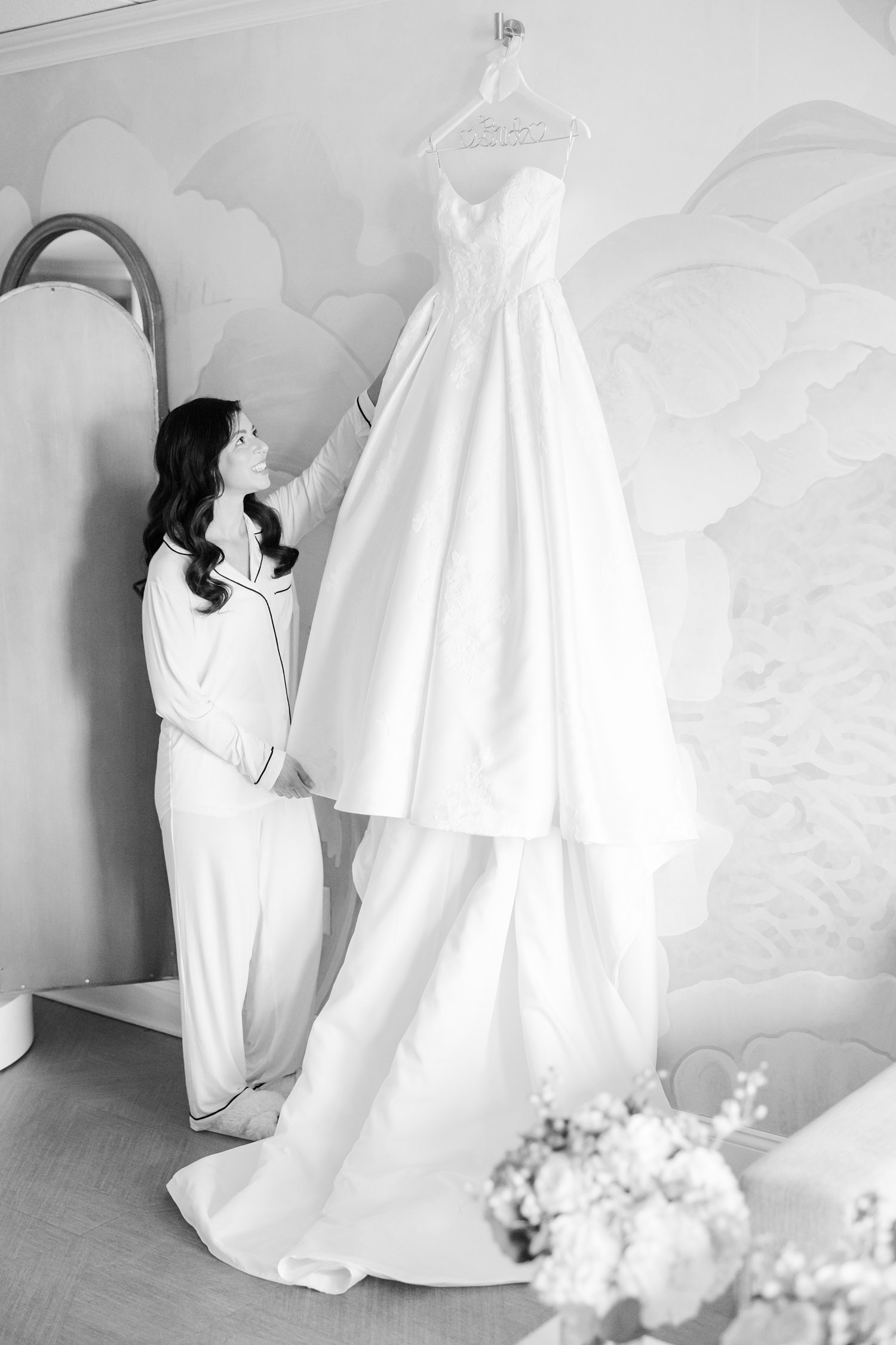 Black and white photo of bride admiring her wedding dress 