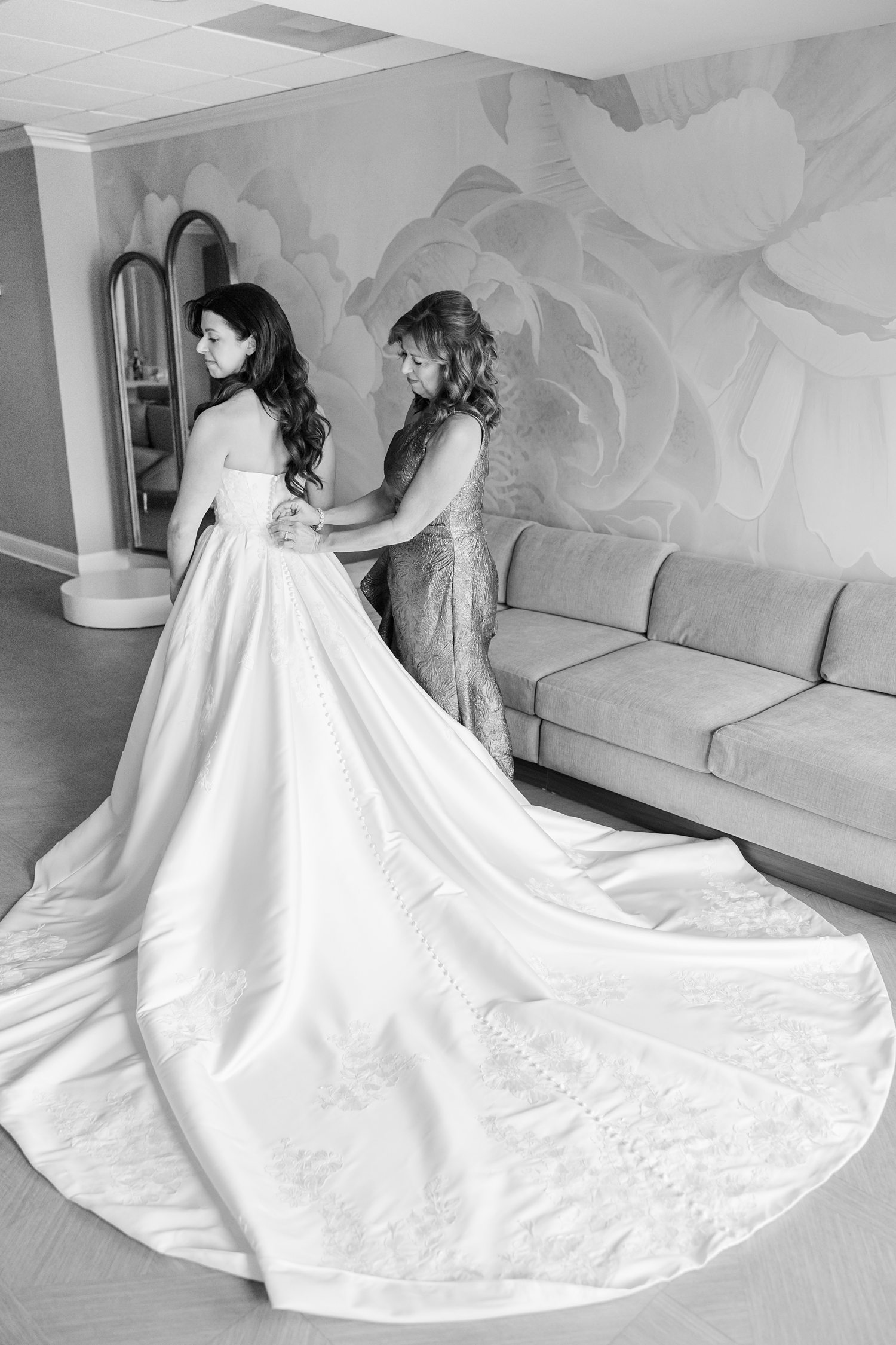 Mother of the bride helping the bride with her gown before a winter wedding 