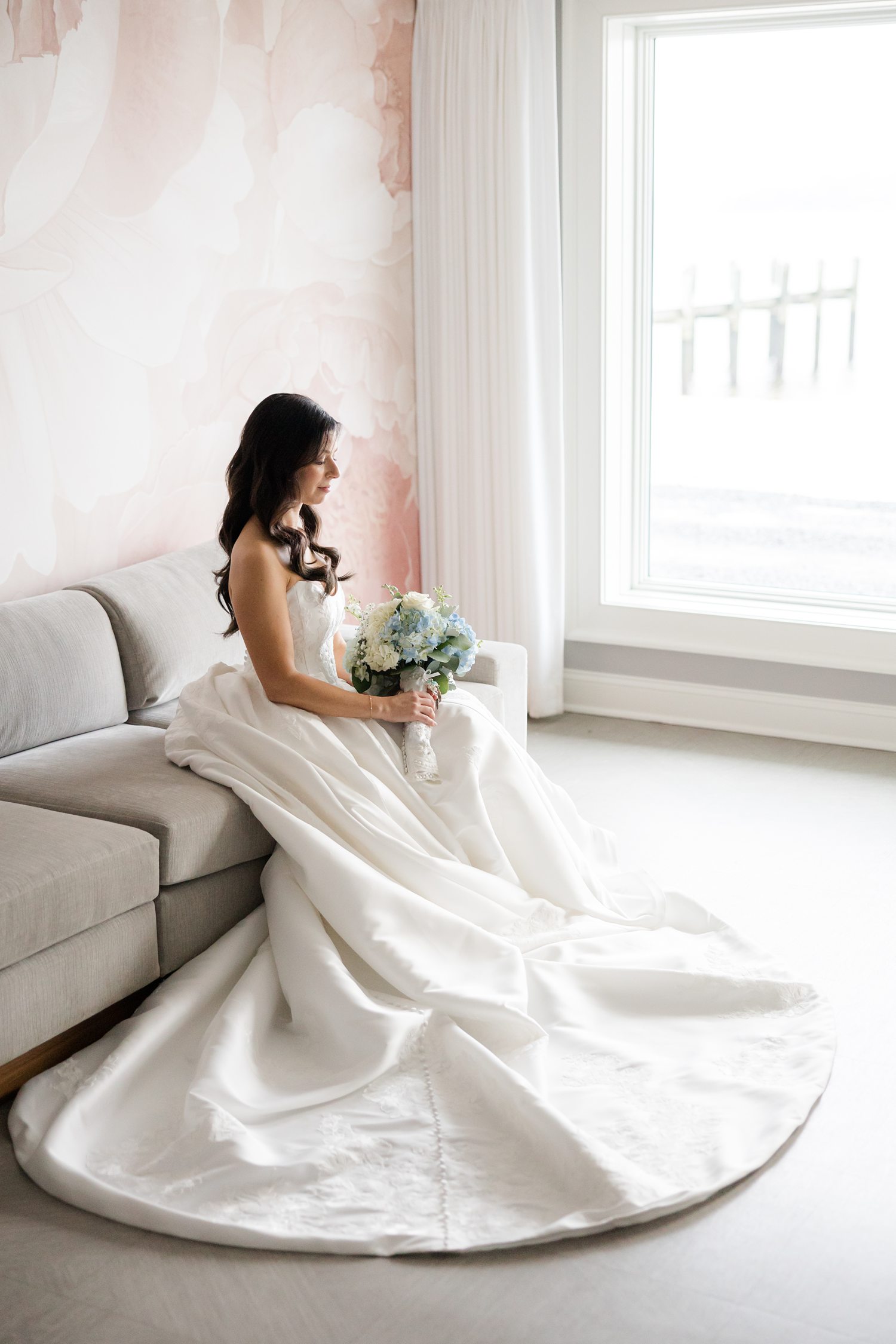 Bride in her wedding gown seated holding a blue and white bouquet 