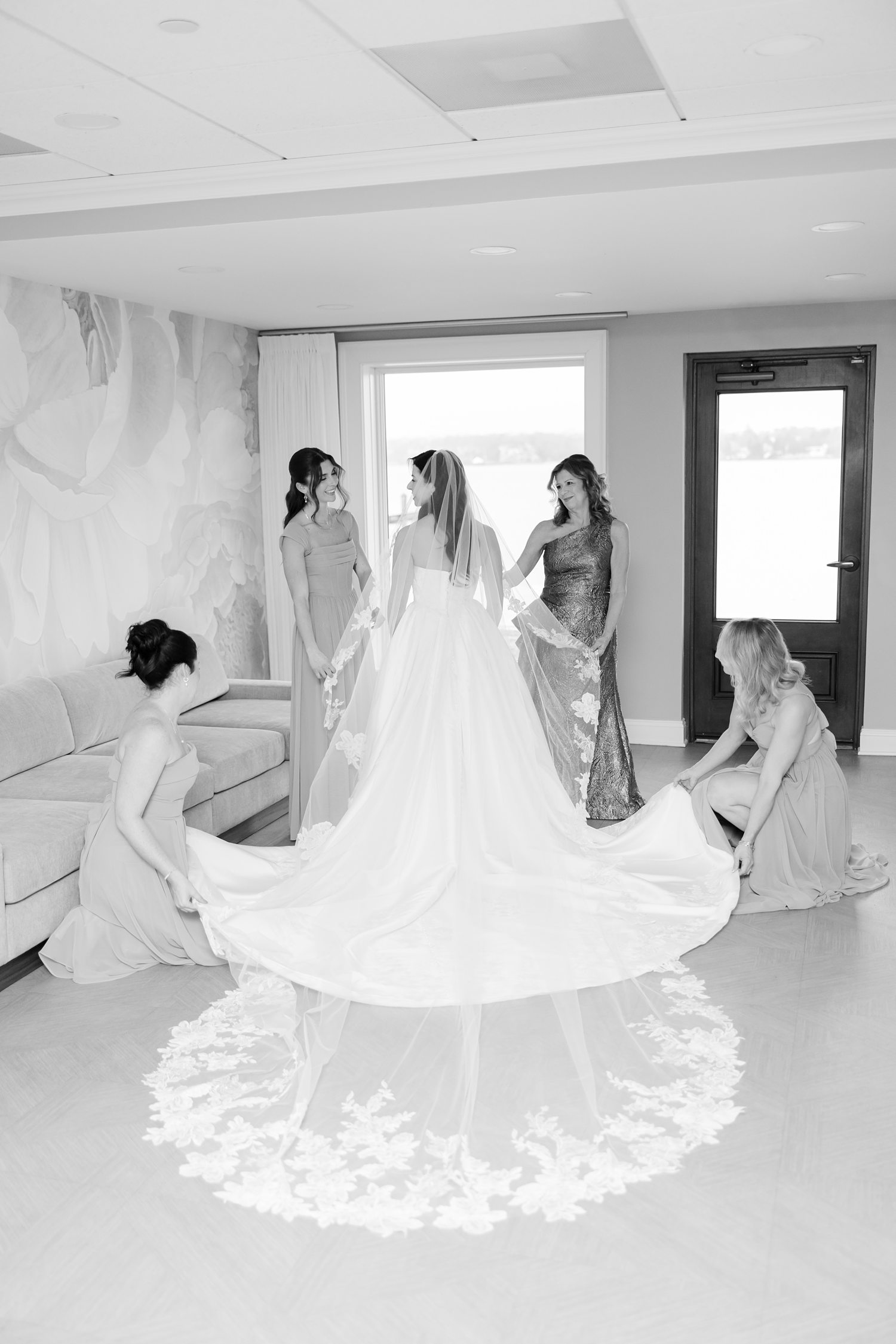 Bridesmaids fluffing the bride’s long gown before the ceremony 