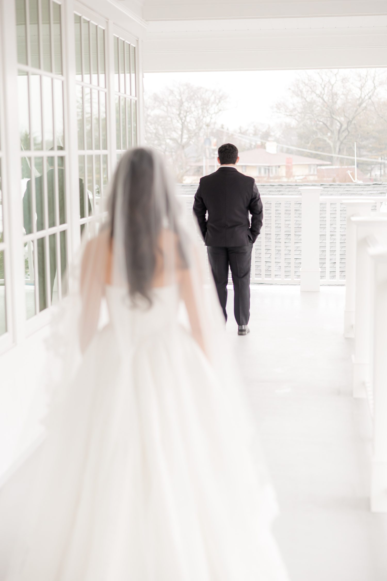 Brides standing behind the groom for a first look on the balcony 