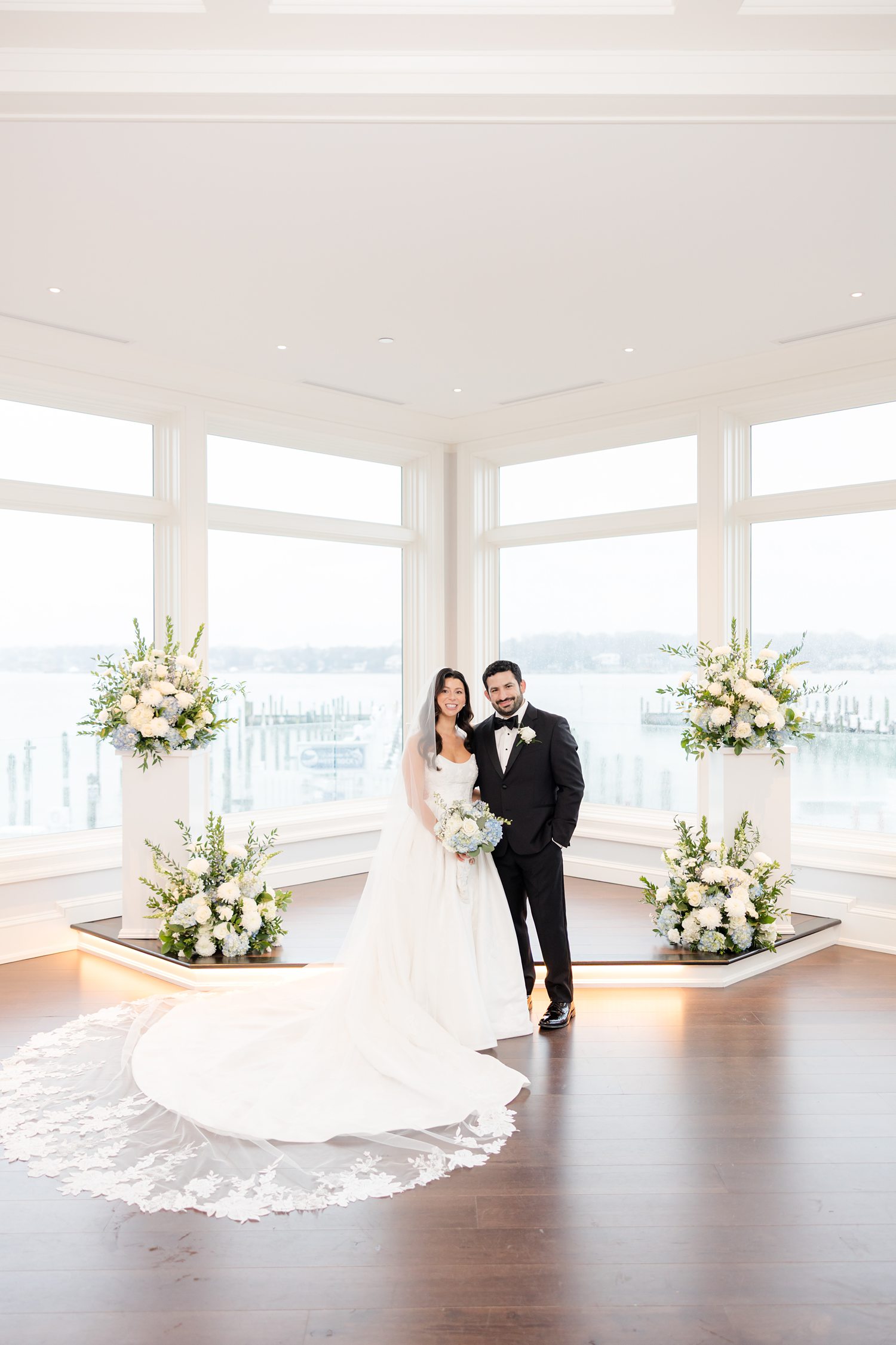 Portrait bride and groom between floral pillars at Clarks Landing Yacht Club ceremony space