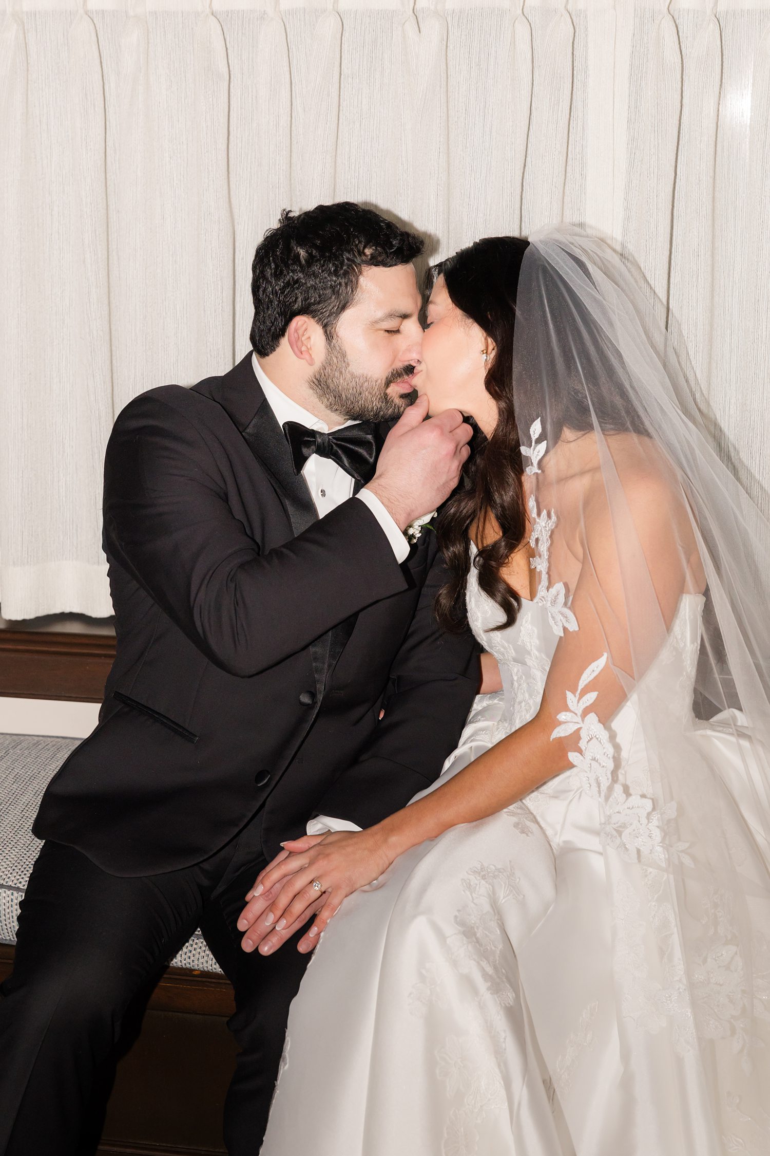 Bride and groom kissing while the groom hold's the bride's chin