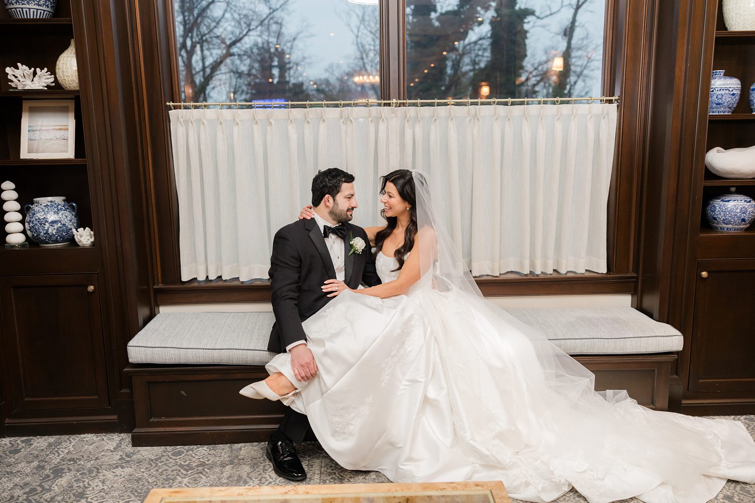 Bride and groom seated together in a cozy indoor daybed