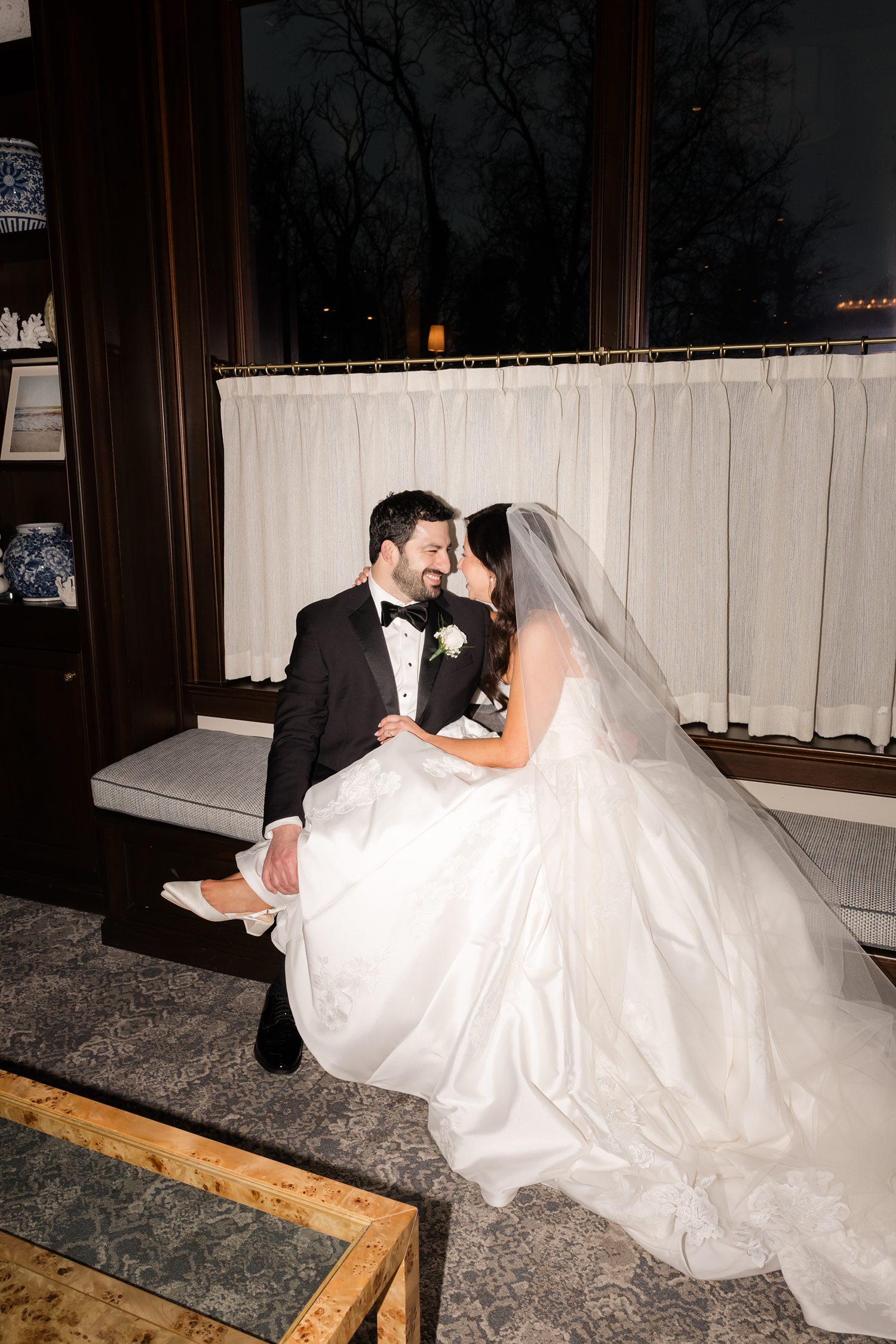 Bride and groom smiling at each other with the bride's feet on the groom's lap
