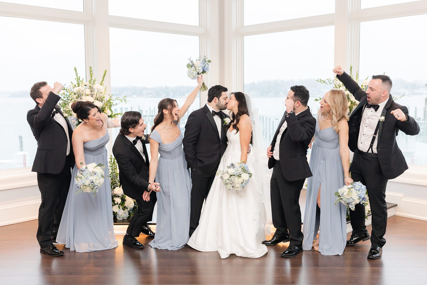 Wedding party cheering while the couple kisses at Clarks Landing Yacht Club ceremony space
