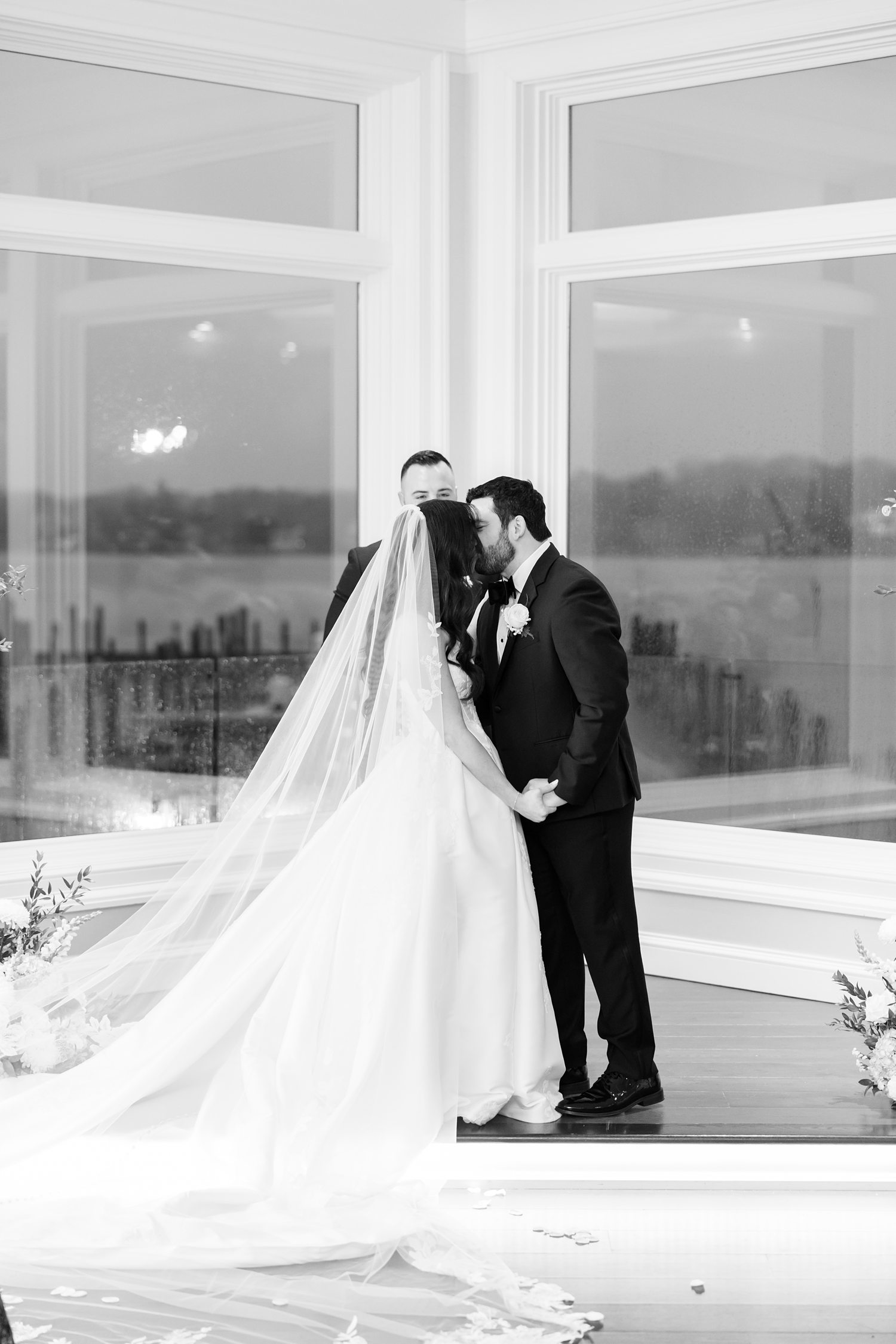 Black and white first kiss photo at the altar during a Clarks Landing Yacht Club wedding ceremony