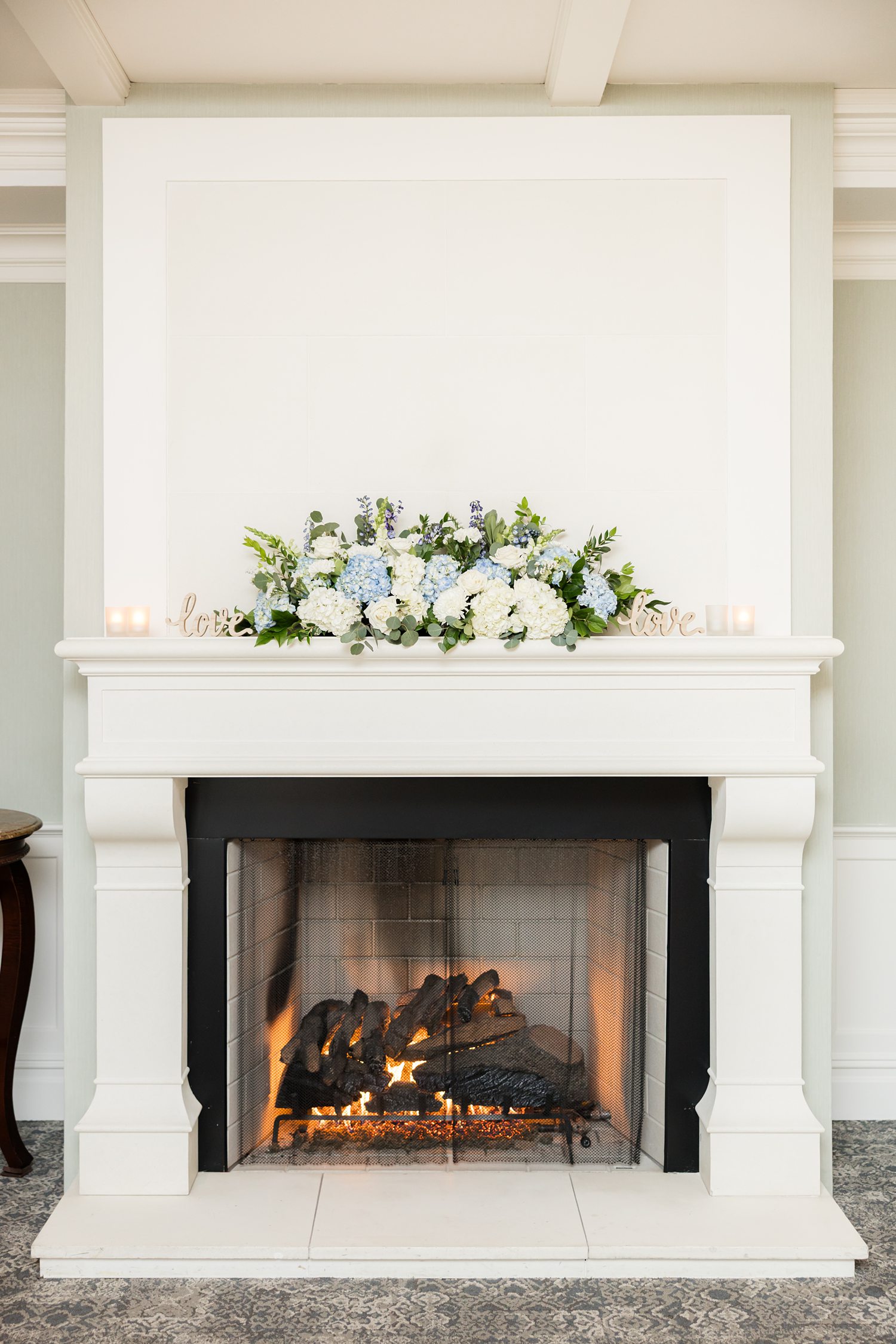 Fireplace decorated with white and blue wedding flowers