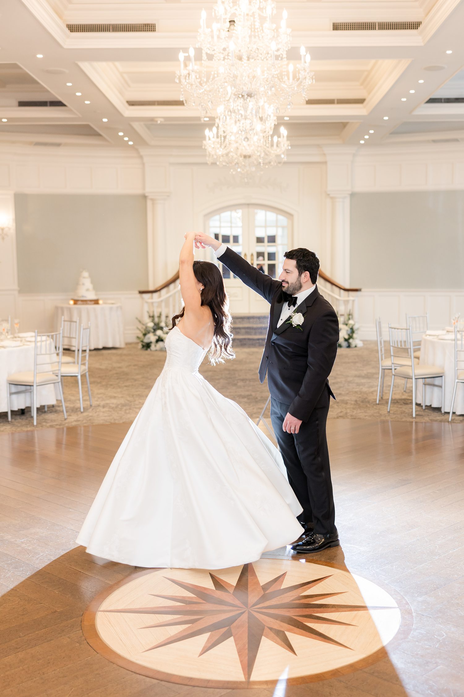 Groom twirls bride in the ballroom