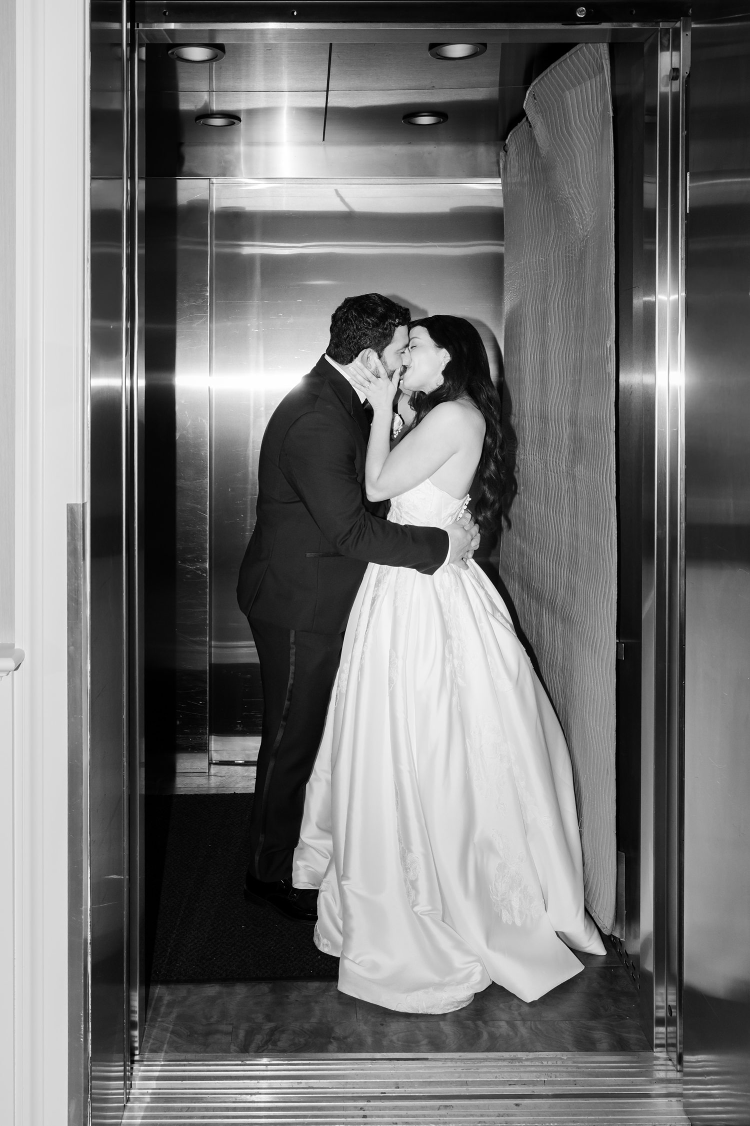 Black and white elevator portrait of bride and groom kissing