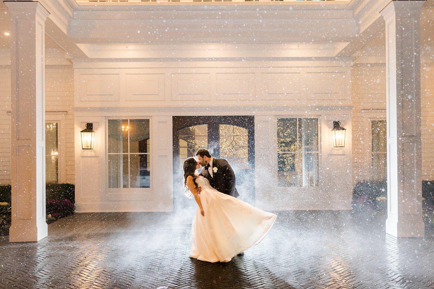 Bride and groom kiss in the snow outside Clarks Landing Yacht Club at night
