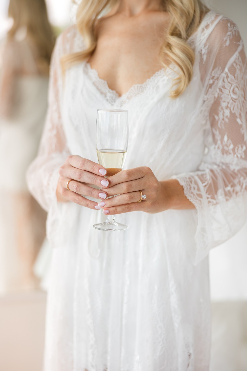 Bride holding a champagne glass in her lace robe