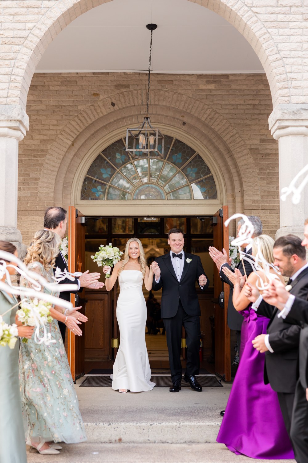 Newlyweds exiting the church with ribbon wands