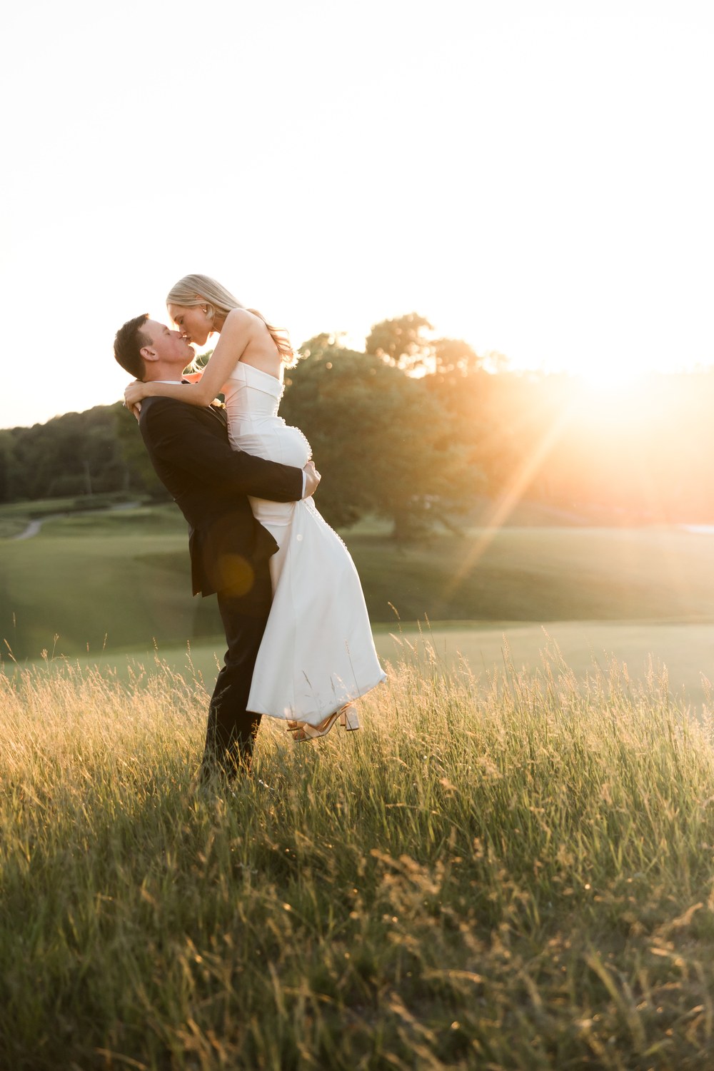 Groom lifting the bride at sunset
