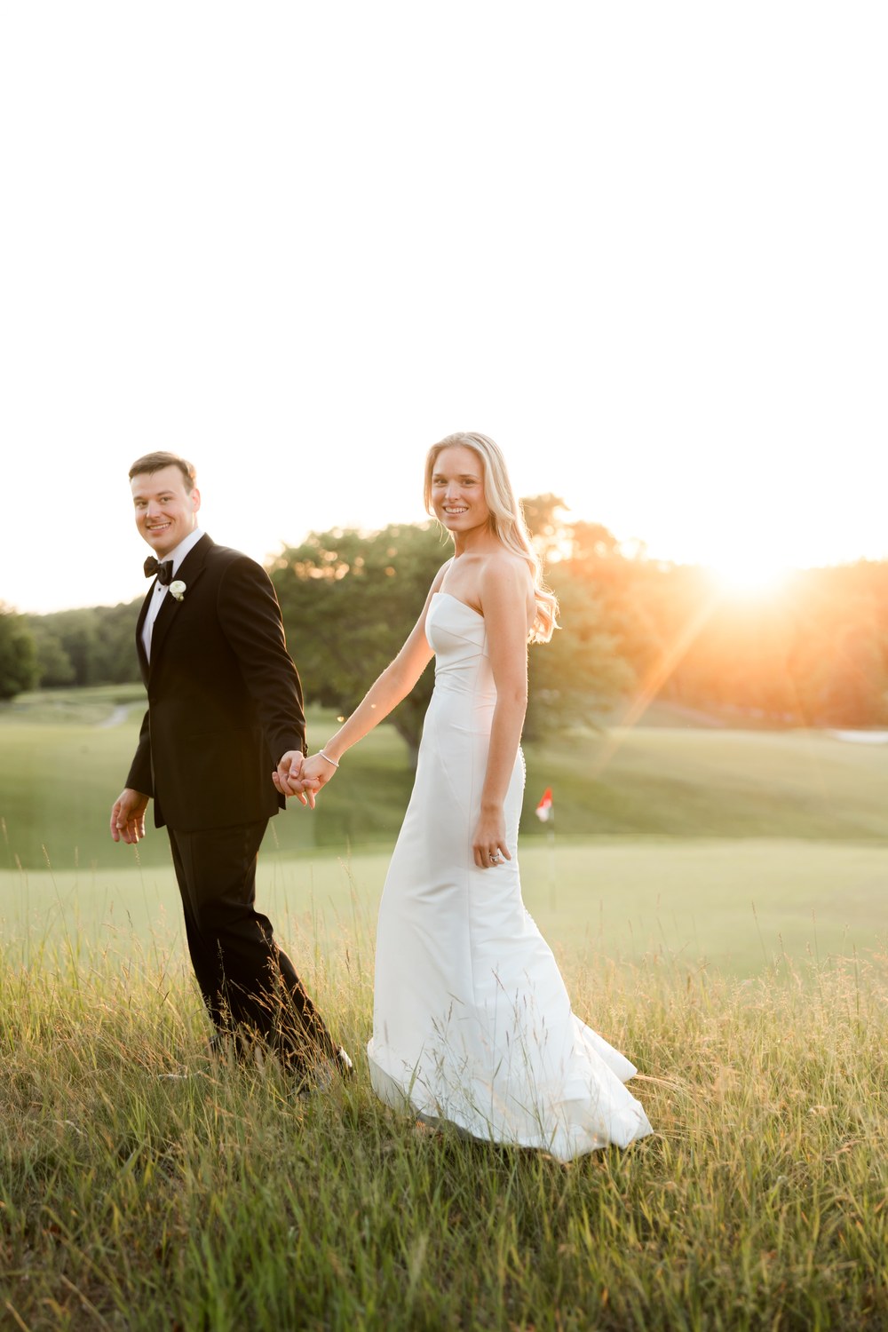 Newlyweds walking hand in hand at sunset