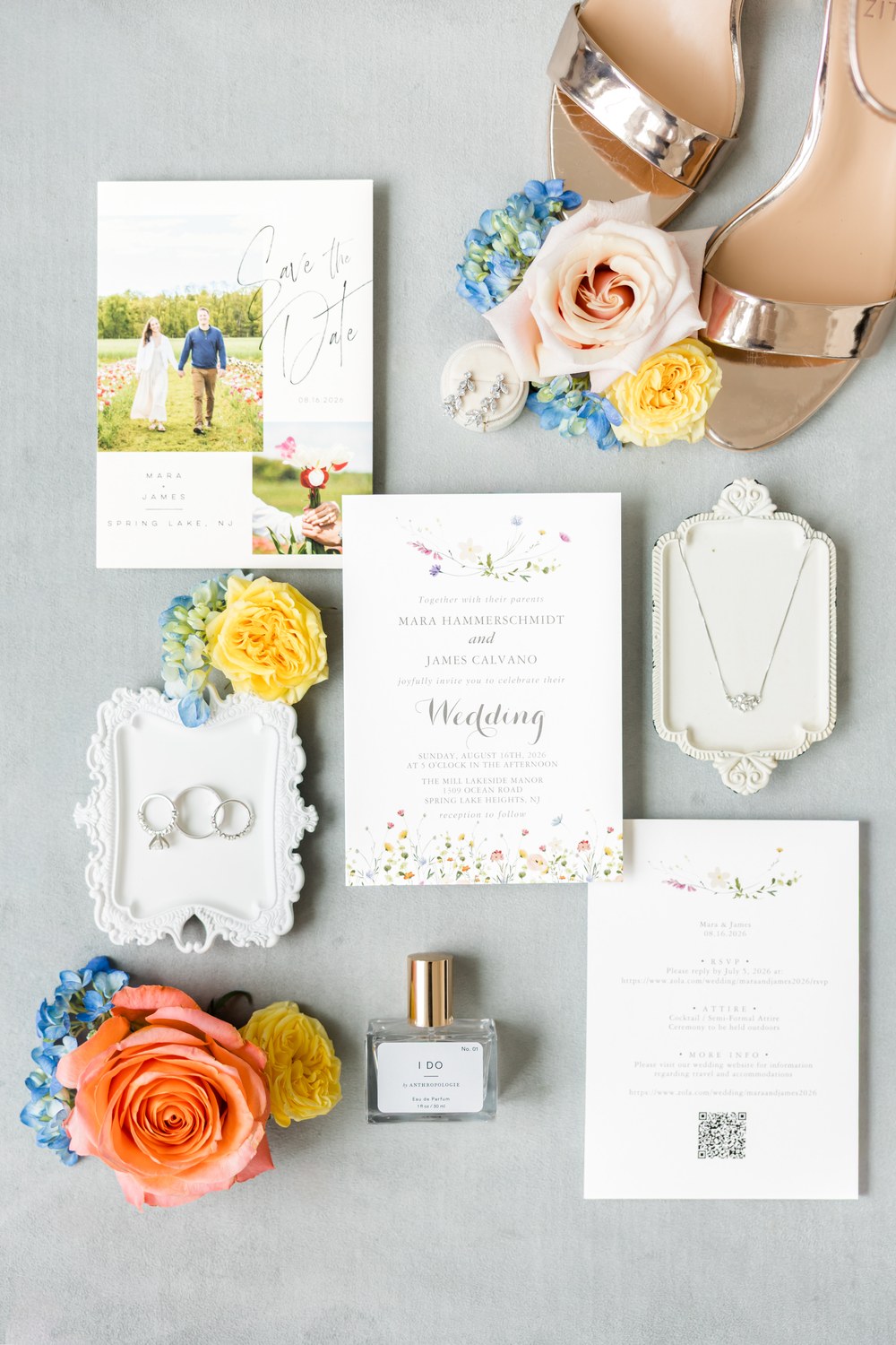 Wedding invitation suite flat lay with pastel flowers and gold bridal shoes