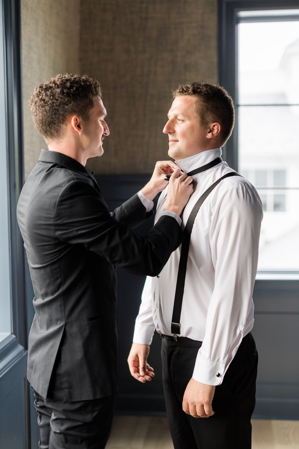 Groomsman helping the groom with his bow tie