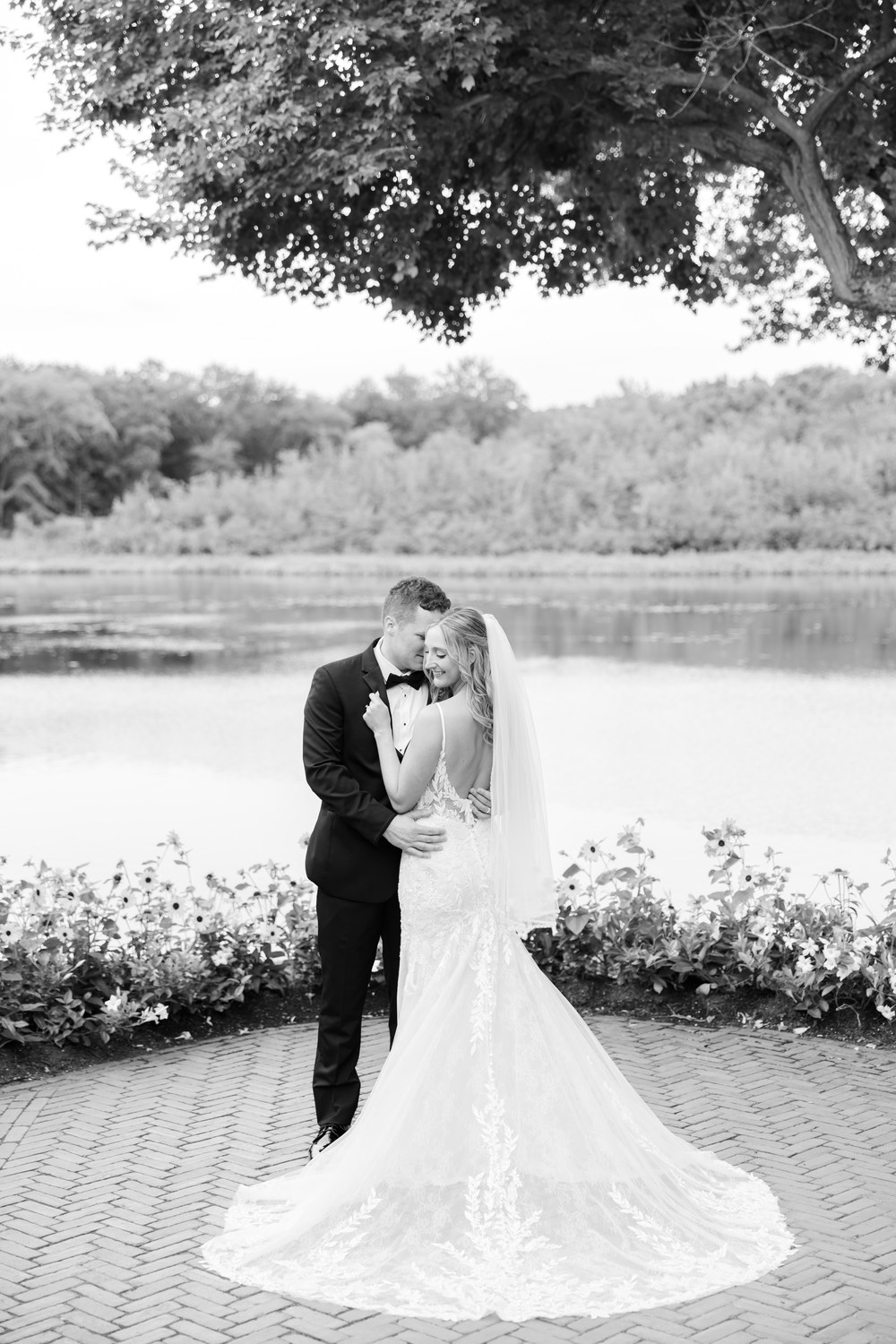 Black and white photo of the bride and groom kissing by the lake