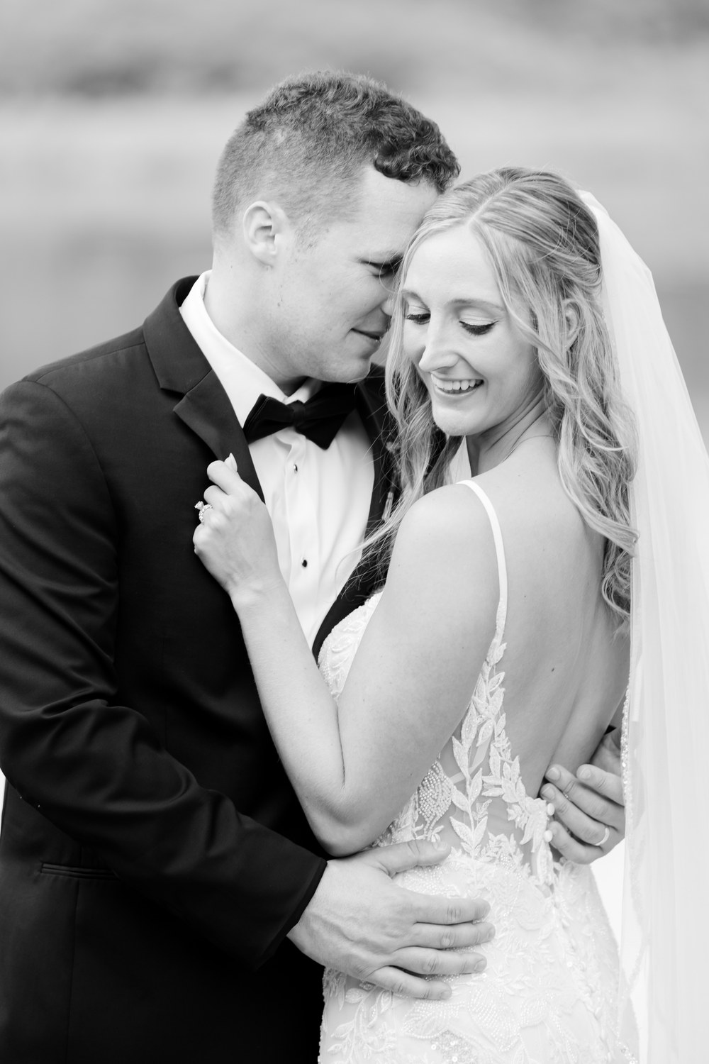 Black and white close portrait of the groom embracing the bride