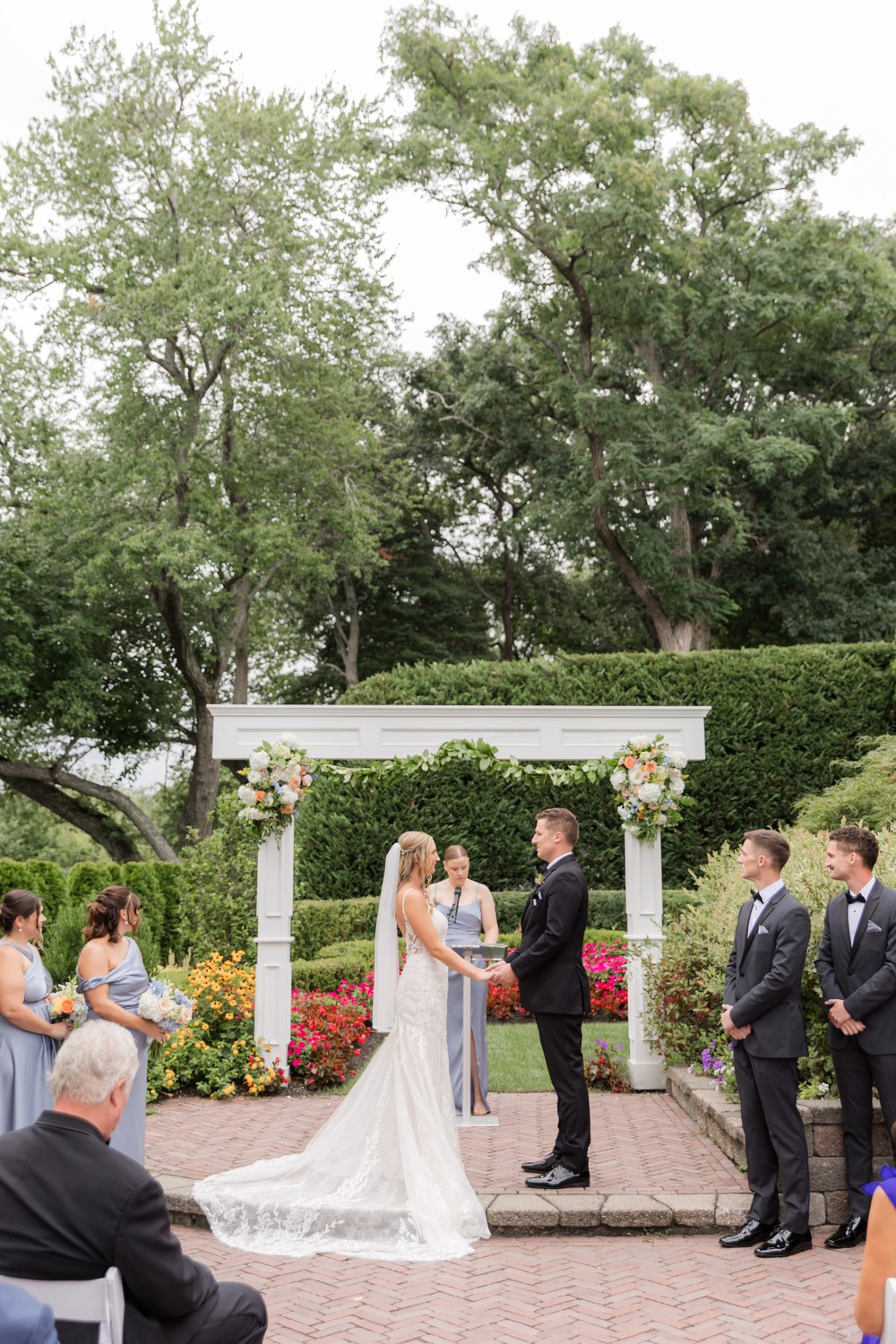 Bride and groom exchanging vows under the floral arch