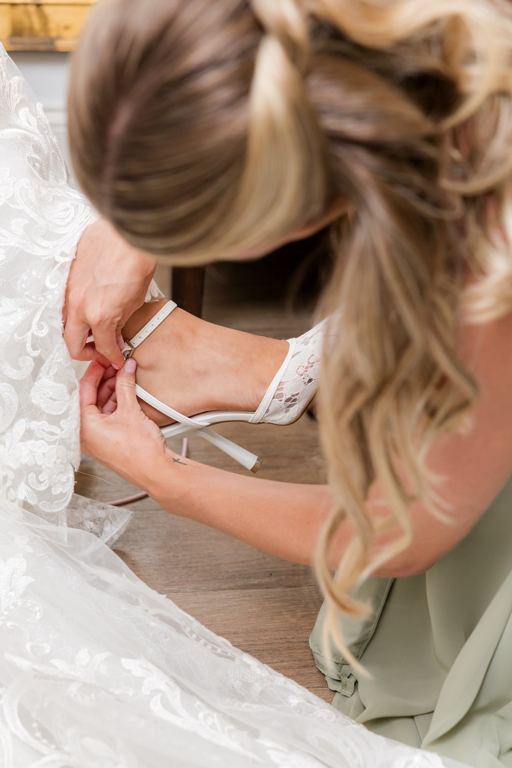 Bridesmaid helping the bride into her wedding shoes