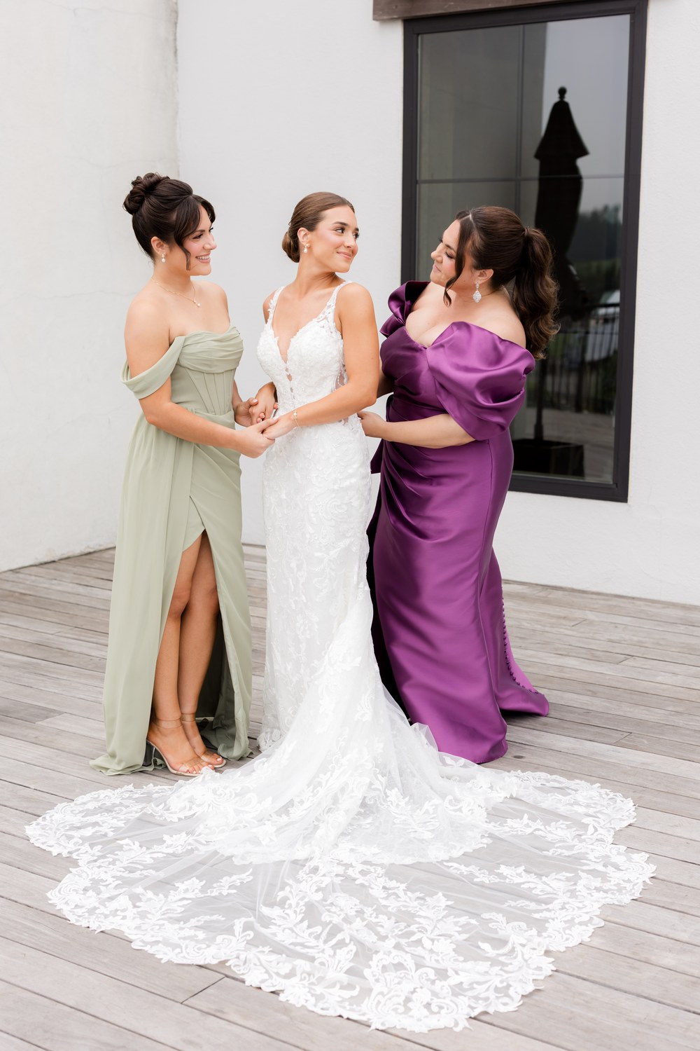 The bride laughing with two women as she finishes getting ready