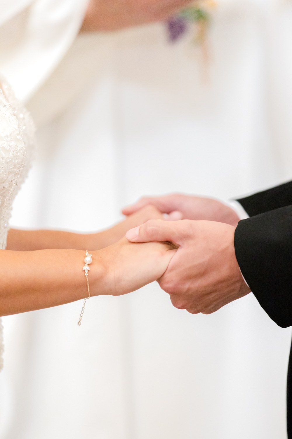 Close-up of the bride and groom holding hands