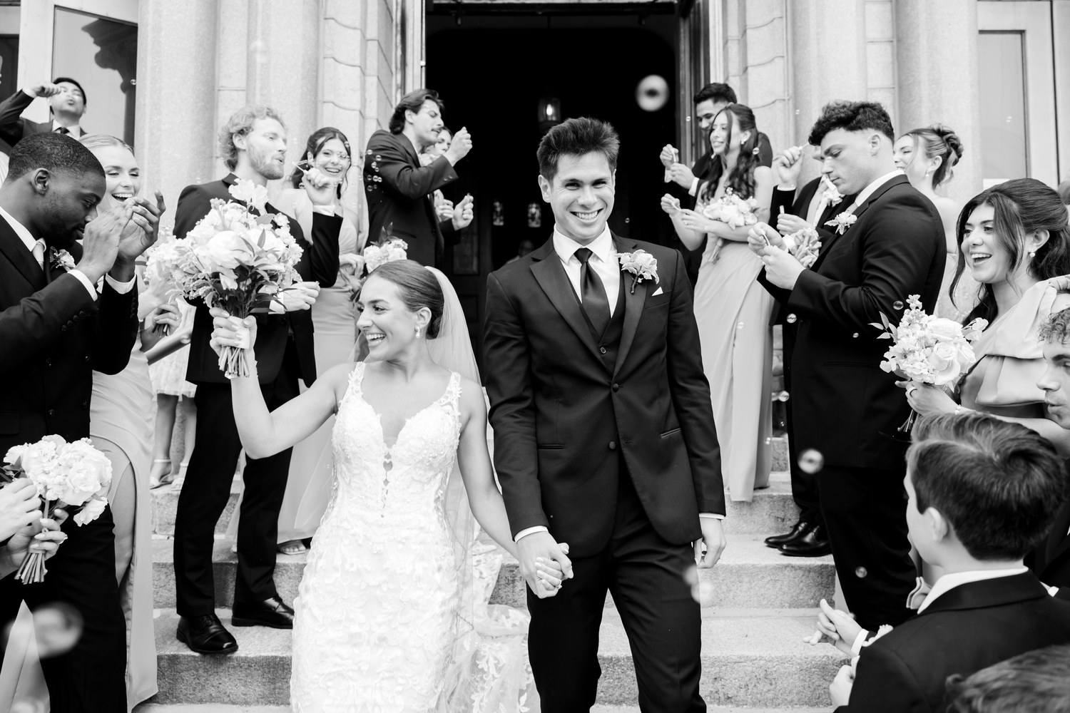 Black and white photo of wedding guests cheering outside the church
