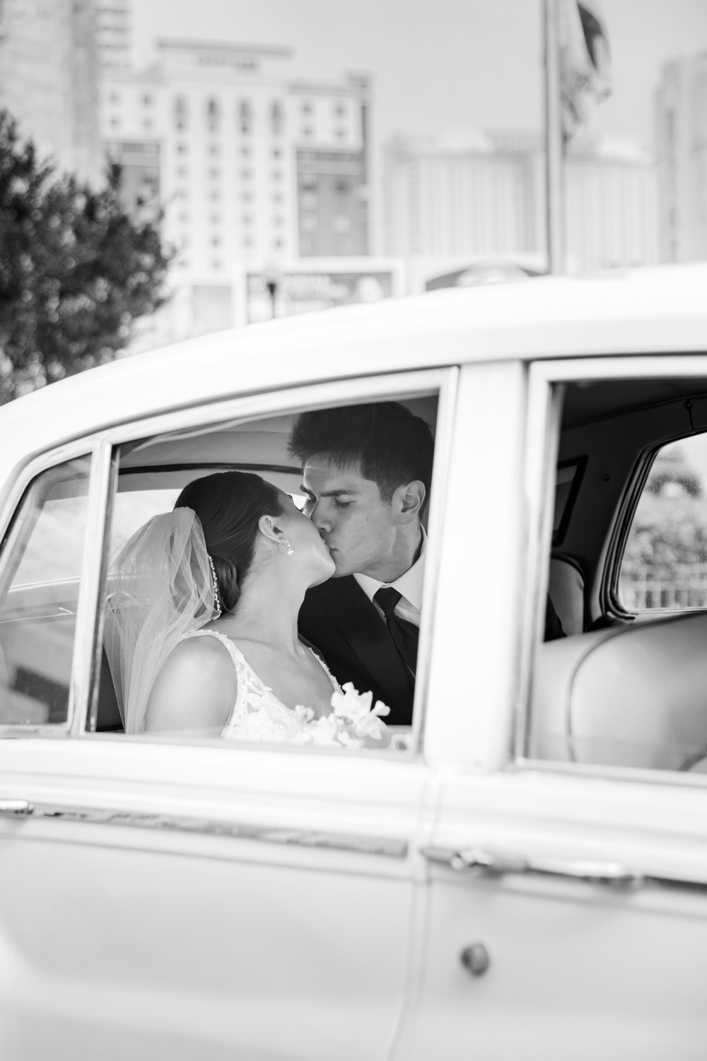 Black and white photo of the couple kissing in the wedding car