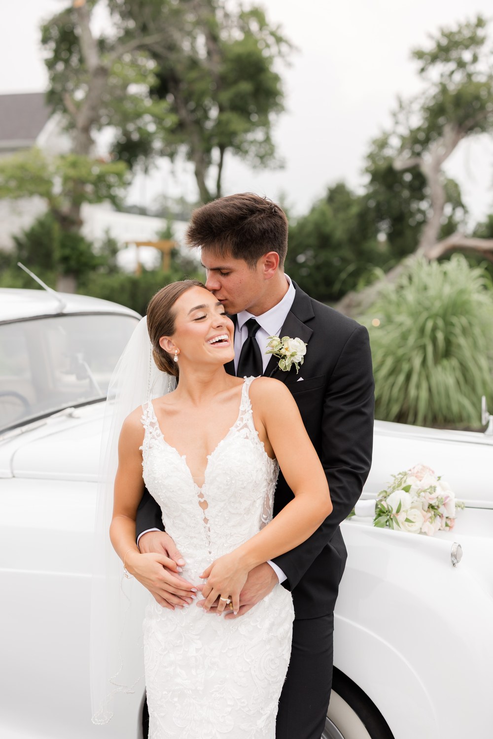 The bride and groom embracing by the vintage car at Renault Winery
