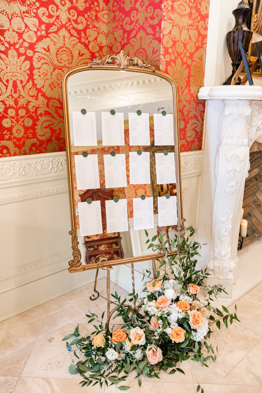 Gold-framed mirror seating chart decorated with peach florals at Ashford Estate